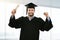 Cheerful smiling graduate wearing gown at graduation ceremony