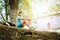 Cheerful smiling young female backpacker sitting on the old stone castle fance and enjoying a rest time on the Way of Camino de Sa