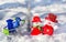 Cheerful snowmen on a silvery New Year tree background with a trolley full of Christmas toys in the snow on the snow