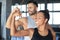 Cheerful sportive couple training together and showing biceps at the gym