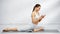 Cheerful sportswoman using smartphone on yoga