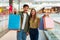 Cheerful Spouses Showing Shopping Bags To Camera Standing In Mall