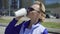 Cheerful stylish businesswoman drinking coffee outside on urban background