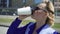 Cheerful stylish businesswoman drinking coffee outside on urban background