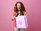 Cheerful stylish woman isolated on pink with shopping bag