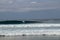 Cheerful Surfer Riding Big Foaming Ocean Wave in Sunny Nature. Man surfing on a cool surfboard in the summer sun near the idyllic