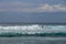 Cheerful Surfer Riding Big Foaming Ocean Wave in Sunny Nature. Man surfing on a cool surfboard in the summer sun near the idyllic