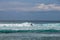 Cheerful Surfer Riding Big Foaming Ocean Wave in Sunny Nature. Man surfing on a cool surfboard in the summer sun near the idyllic