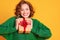 Cheerful surprised   woman  laughs with closed eyes holds a Christmas gifts on a colored yellow background