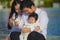 Cheerful and sweet wife and husband couple with mother holding baby girl and man playing with little daughter in Asian Chinese