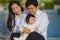 Cheerful and sweet wife and husband couple with mother holding baby girl and man playing with little daughter in Asian Chinese