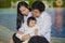 Cheerful and sweet wife and husband couple with mother holding baby girl and man playing with little daughter in Asian Chinese