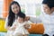 Cheerful and sweet wife and husband couple with mother holding baby girl and man playing with little daughter in Asian Korean