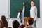 cheerful teacher near schoolgirl writing on