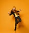 Cheerful teen girl with long red hair in knitted hat, yellow glasses and t-shirt is dancing cool like a hip-hop rap star