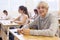 Cheerful teen schoolboy sitting in classroom during lesson