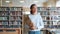 Cheerful teenage girl walking with books in high school library smiling