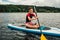 Cheerful teenager sitting on a sap surf and rowing with an oar