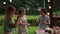 Cheerful teenagers dancing at a birthday party. Two girls and a boy in a birthday hat have a fan around the set table