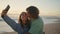 Cheerful teenagers making selfie sunset beach closeup. Young man kissing woman