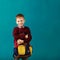 Cheerful thoughtful little school boy in school uniform with big