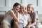 Cheerful three-generation family sitting on couch enjoy time together