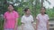 Cheerful three Thai teen girls in casual dress talking and walking leisurely together on the footpath in the rural village.