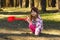 Cheerful todler girl showing the way in the forest with a red shovel