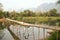 Cheerful Tourist crossing bamboo bridge, limestone view, laos