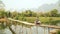 Cheerful Tourist crossing bamboo bridge motorbike, limestone view, laos