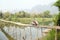 Cheerful Tourist crossing bamboo bridge motorbike, limestone view, laos