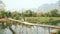 Cheerful Tourist crossing bamboo bridge motorbike, limestone view, laos