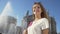 Cheerful tourist girl standing near fountain