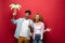 Cheerful travelers holding paper palm, isolated on red