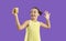 Cheerful trendy kid girl influencer record video vlog and makes selfie on purple background.