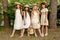 Cheerful tween girls with basket of flowers, posing near blooming shrub in park