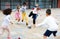 Cheerful tween schoolchildren playing with ball near school