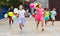 Cheerful tweenagers with balloons in hands running on city street
