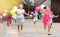 Cheerful tweenagers with balloons in hands running on city street