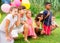 Cheerful tweenagers with colored balloons posing together in summer park