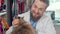 Cheerful veterinarian smiling joyfully, petting adorable cat at his clinic