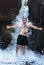 A cheerful wet man in shorts bathes in a river under a waterfall