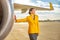 Cheerful woman airline worker standing near airplane at airfield