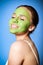 Cheerful woman applying green mask