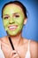 Cheerful woman applying green mask