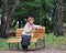 The cheerful woman of average years sits on a bench with a cup of tea in a hand