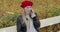 Cheerful woman in beret speaking on phone