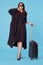 cheerful woman in black coat business trip travel passenger blue background