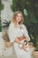 Cheerful woman with blonde curly hair holding white coconuts in tropical resort