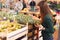 Cheerful woman choosing pineapple fruits during shopping in fruit store